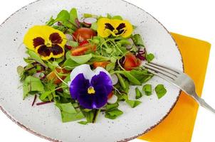 Vegetable salad with edible flowers on white background. photo