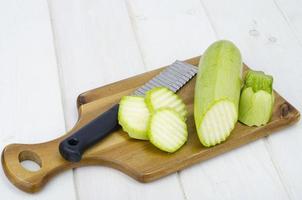 Calabacín fresco verde joven sobre mesa de madera para cocinar foto