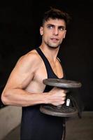 Young American man lifting a dumbbell at gym.