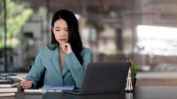 Image of an Asian woman who is tired and overthinking from working with a tablet at the office. photo