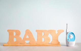 Baby monitor and wooden letters on table against color background photo