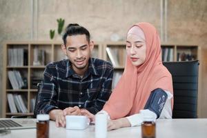 estilo de vida del seguro de la clínica médica de las personas. un joven amante de una pareja musulmana está haciendo sus chequeos médicos en casa. el marido se preocupa por la salud de su esposa, que es una hermosa mujer que lleva un hiyab. foto