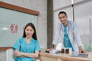 Healthcare partners team, portrait of two young doctors of Asian ethnicity in uniform with stethoscope, smiling and looking at camera in clinic, persons who expertise in professional treatment. photo