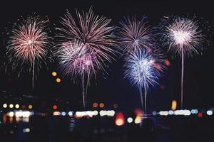 Fuegos artificiales con siluetas de personas en eventos de vacaciones.Fuegos artificiales de año nuevo en la playa. foto