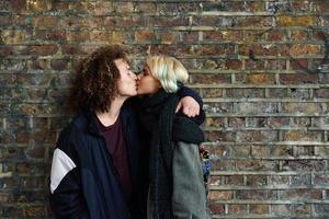 Young couple enjoying Camden town in front of a brick wall typical of London photo