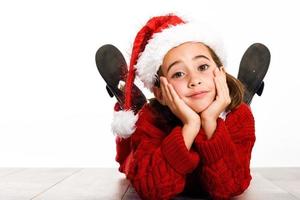 Adorable little girl wearing santa hat laying on wooden floor photo