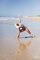 Caucasian blonde woman practicing yoga in the beach photo