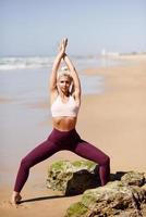 Caucasian blonde woman practicing yoga in the beach photo
