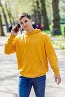 Young urban man using smartphone walking in street in an urban park in London. photo