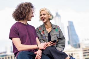 Happy couple talking sitting near River Thames. photo