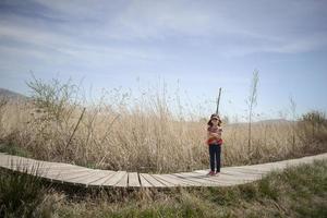 Niña caminando por un sendero de tablas de madera en un humedal foto