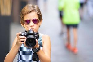 Little girl making photo with DSLR camera on city street
