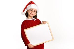 Little girl wearing santa hat holding blank board