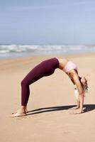 mujer rubia caucásica practicando yoga en la playa foto