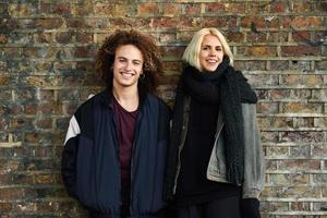 Young couple enjoying Camden town in front of a brick wall typical of London photo