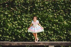 Happy 9-year-old girl in a pretty dress playing photo
