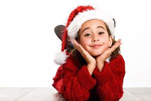 Adorable little girl wearing santa hat laying on wooden floor photo