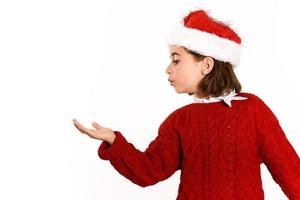 Adorable little girl wearing santa hat blowing to her hand photo