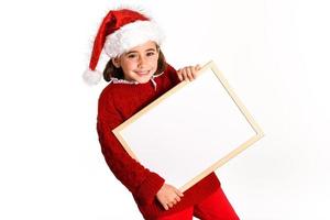 Little girl wearing santa hat holding blank board