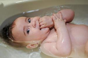 Baby girl four months old having her bath photo