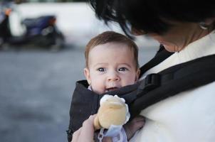 madre cargando a su niña en un portabebé foto