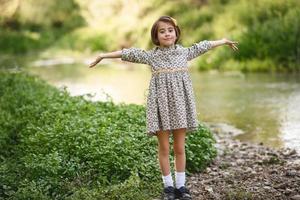 Little girl in nature stream wearing beautiful dress photo