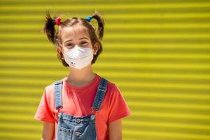 Child girl wearing a protection mask against coronavirus during Covid-19 pandemic photo