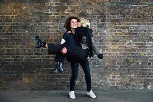 Man holding his girlfriend in his arms in front of a brick wall typical of London photo