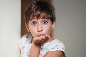 Funny little girl, eight years old, blowing a kiss photo