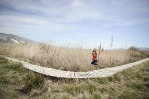 Little girl walking on a path of wooden boards in a wetland photo