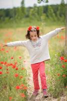 linda niña divirtiéndose en un campo de amapolas foto