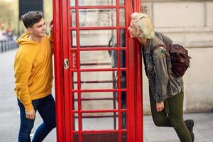 Young couple of friends near a classic British red phone booth