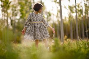 Little girl in nature field wearing beautiful dress photo