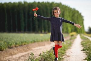 Little girl walking in nature field wearing beautiful dress photo