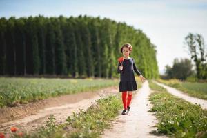 Little girl walking in nature field wearing beautiful dress photo