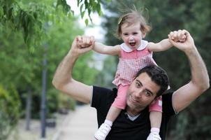 Little girl walking on the shoulders of her father photo