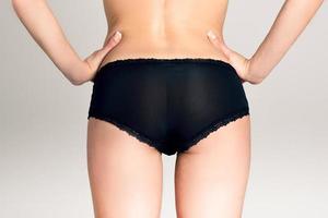 Female ass wearing black panties against white background photo