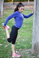 Happy young woman stretching before running outdoors photo