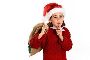 Adorable little girl wearing santa hat carrying gift bag photo