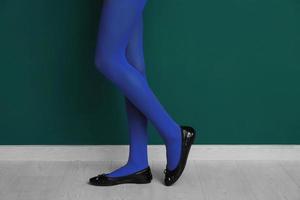 Beautiful woman in stylish shoes near color wall photo