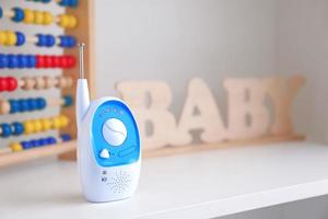 Baby monitor, abacus and wooden letters on shelf photo