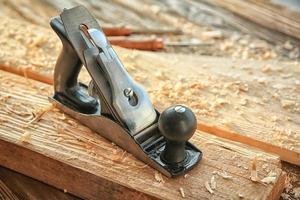 Smoothing plane, wooden boards and sawdust in carpenter's workshop photo