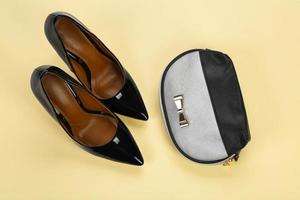 Stylish female shoes with cosmetic bag on color background photo