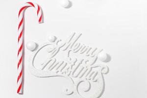 Merry Christmas card with red candy cane on white background with hard light photo