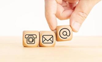 Contact us icons on wooden blocks. Hand holding a dice with communication icon. Copy space