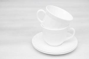 Tazas de cerámica blanca con platillos sobre mesa blanca foto