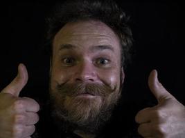 funny face of a man with a beard and mustache close up and showing thumbs up photo