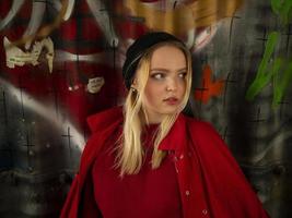 portrait of an attractive young hipster girl in a knitted hat against the wall with inscriptions photo