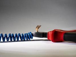 Close up of red pliers and blue twisted wire on white background.Pliers cutting cable photo