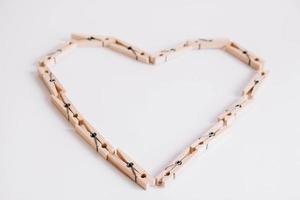 Wooden clothespins on white background which are folded in the form of heart icon photo